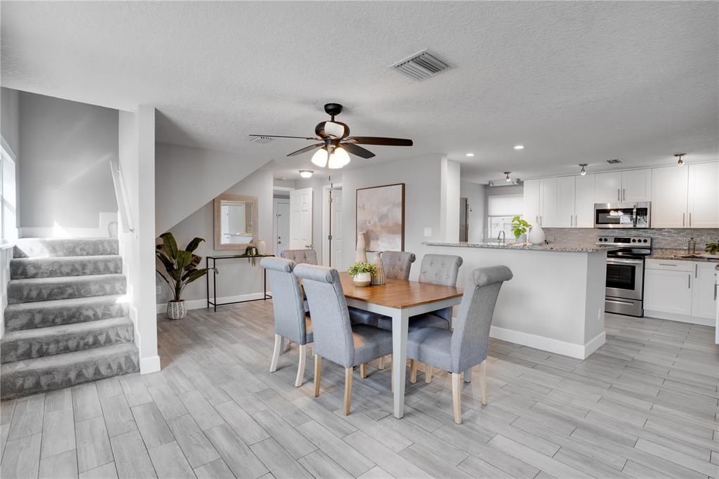 A dining area with a wooden table and gray chairs sits beside a modern kitchen — 7991 24TH AVE N AVENUE N, ST PETERSBURG, FL