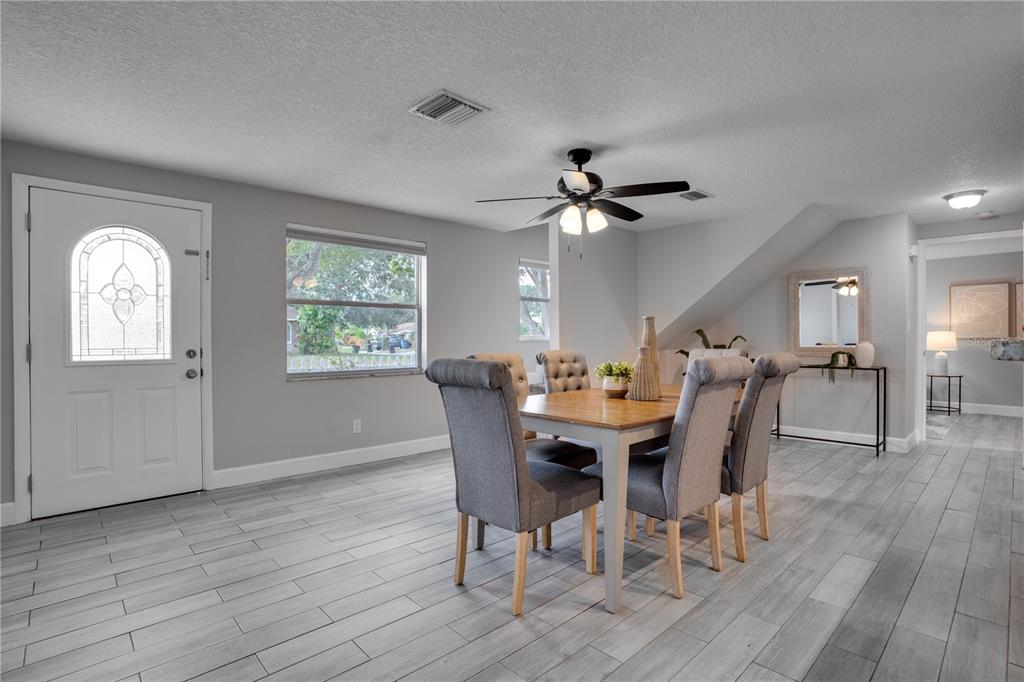 A dining room with gray tile floors, a wooden table, and four upholstered chairs — 7991 24TH AVE N AVENUE N, ST PETERSBURG, FL