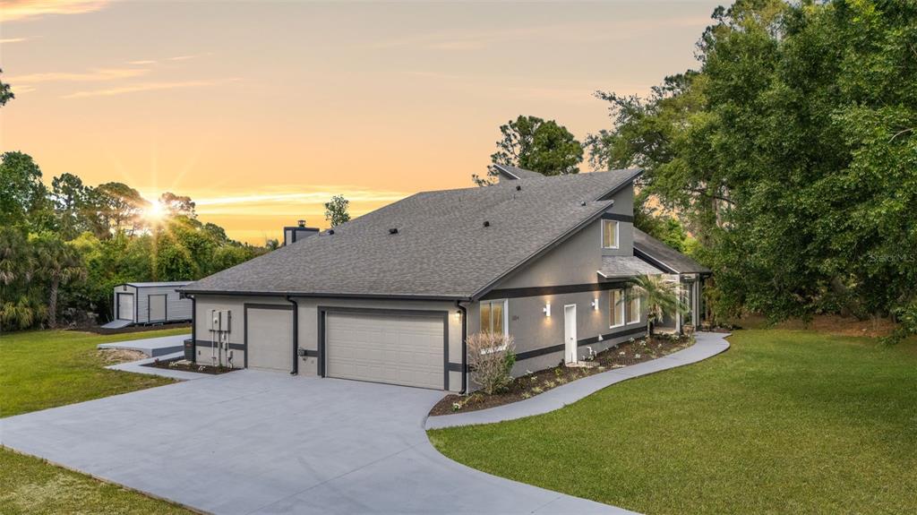 A gray house with a multi-car garage and a paved driveway sits on a lawn — 3884 GOSHAWK PLACE, TITUSVILLE, FL