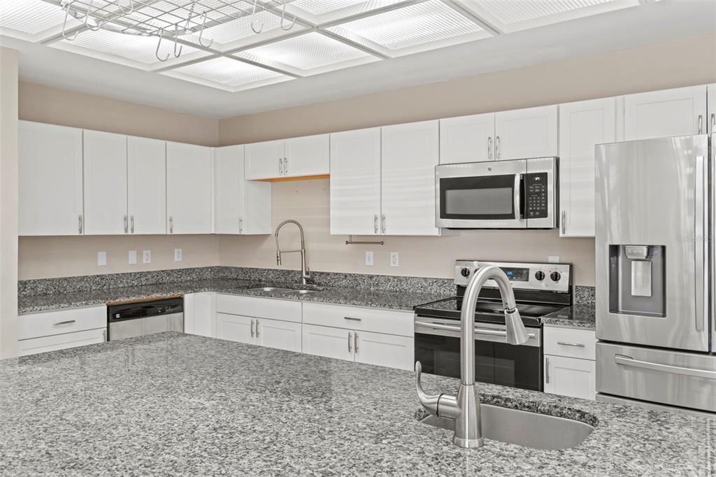 A kitchen features white cabinets, granite countertops, stainless steel appliances, and a large island — 3884 GOSHAWK PLACE, TITUSVILLE, FL