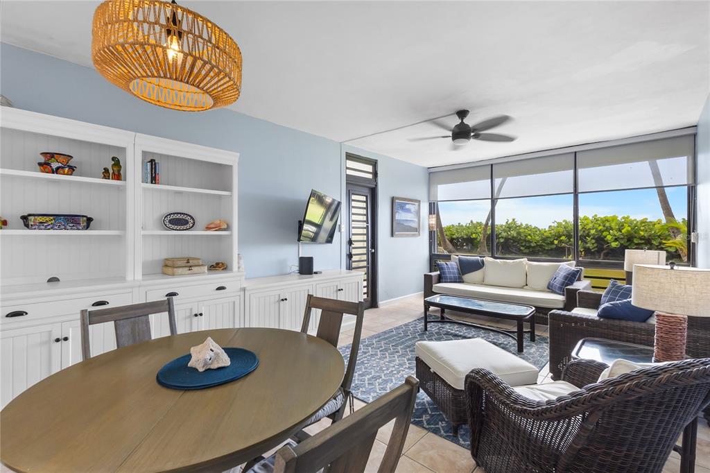 A living and dining area features a wicker pendant light, built-in shelving, and floor-to-ceiling windows — 94 BEACH VILLAGE DRIVE UNIT 94, HUMACAO, PR