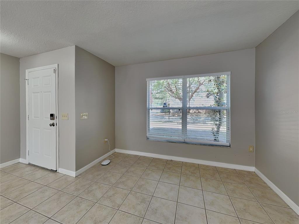 A room with beige tile flooring, light gray walls, a white door, and a large window — 10432 BOYETTE CREEK BOULEVARD, RIVERVIEW, FL