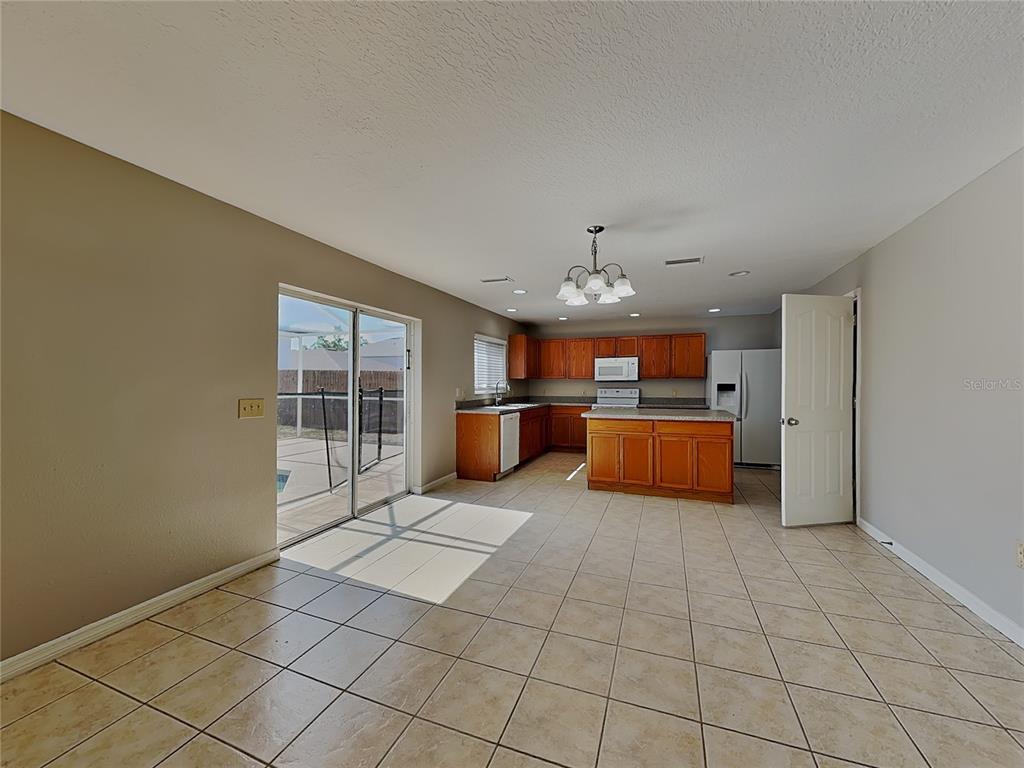 A kitchen with wood cabinets, an island, and tile flooring opens to a patio area — 10432 BOYETTE CREEK BOULEVARD, RIVERVIEW, FL