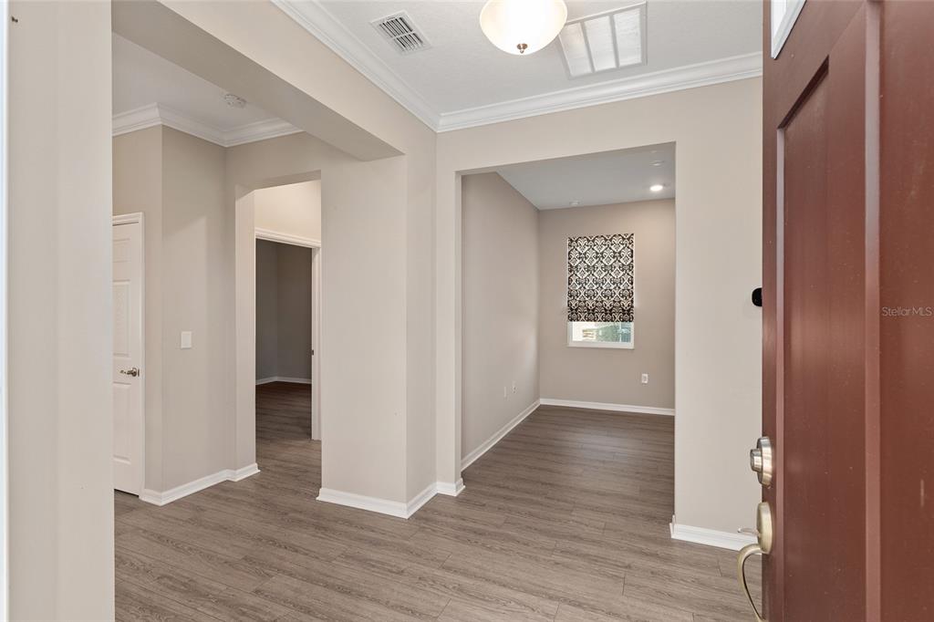 An entryway with light-colored walls and wood-look flooring leads into a room with a window — 9722 SW 102ND TERRACE, OCALA, FL