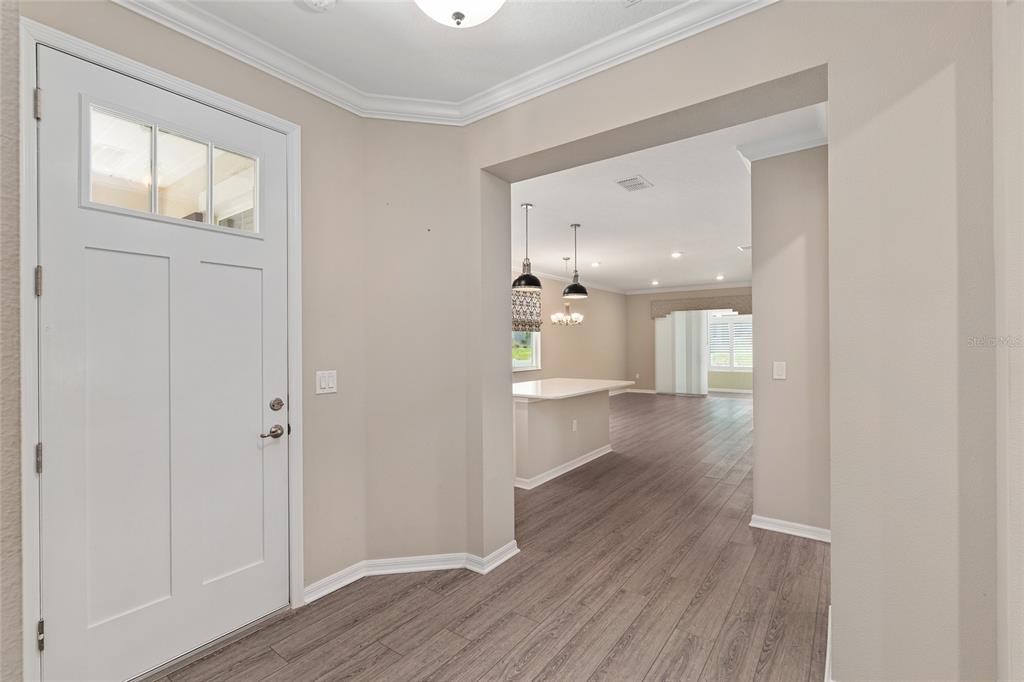 An entryway with wood-look flooring leads into an open-concept kitchen and living area — 9722 SW 102ND TERRACE, OCALA, FL