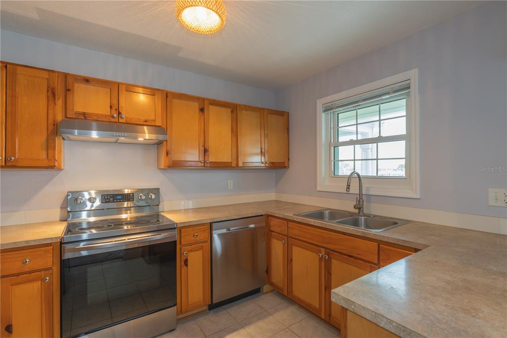 A kitchen with wood cabinets, stainless steel appliances, and light-colored countertops — 123 SEAHORSE DRIVE SE UNIT D, ST PETERSBURG, FL