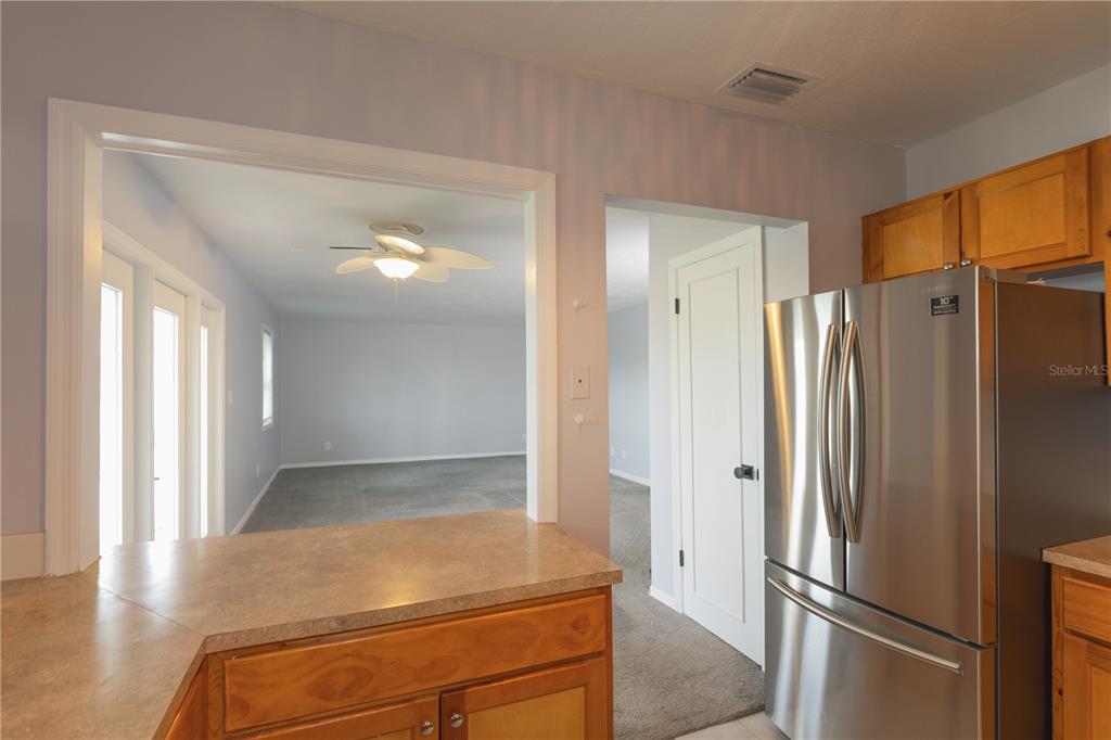 A kitchen with wood cabinets and a stainless steel refrigerator overlooks an adjacent living area — 123 SEAHORSE DRIVE SE UNIT D, ST PETERSBURG, FL