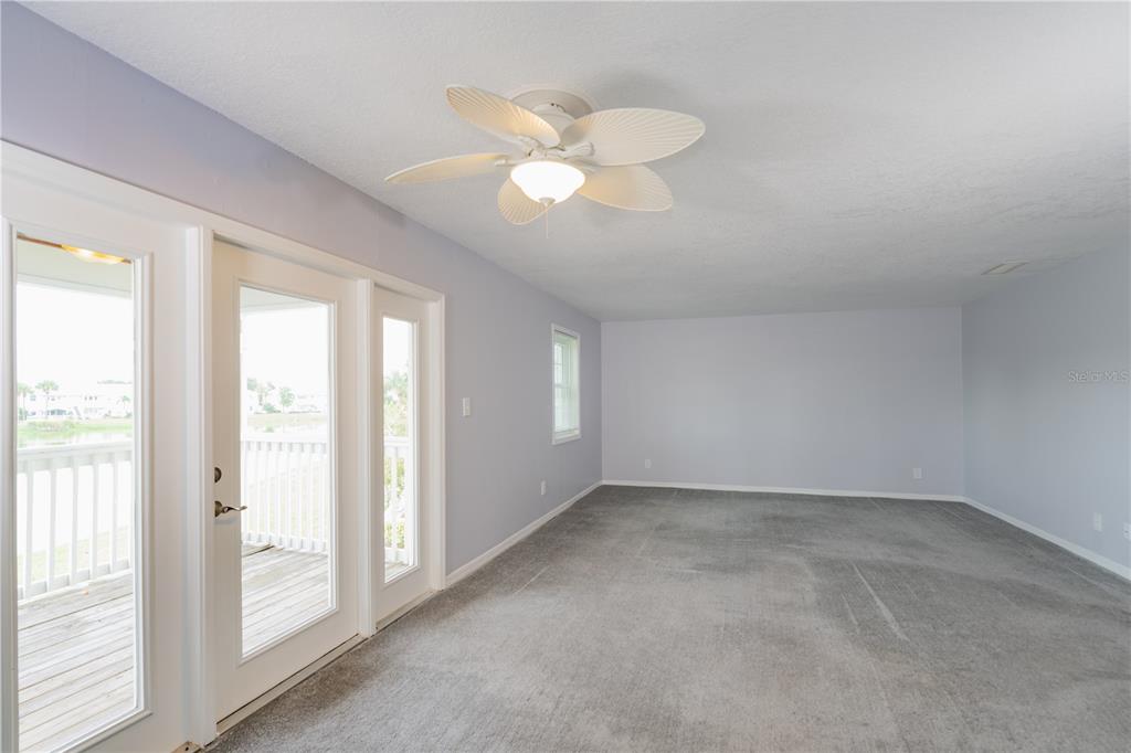 An empty room features gray carpeting, light blue walls, a ceiling fan, and glass doors — 123 SEAHORSE DRIVE SE UNIT D, ST PETERSBURG, FL