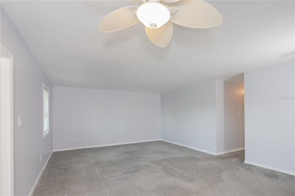 An empty room with light gray walls, gray carpeting, and a white ceiling fan — 123 SEAHORSE DRIVE SE UNIT D, ST PETERSBURG, FL