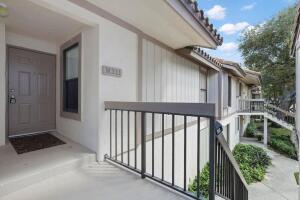 An exterior view of an apartment building entrance with a brown door and metal railing — 3130 Millwood Terrace # 2110, Boca Raton FL 33431, BOCA RATON, FL