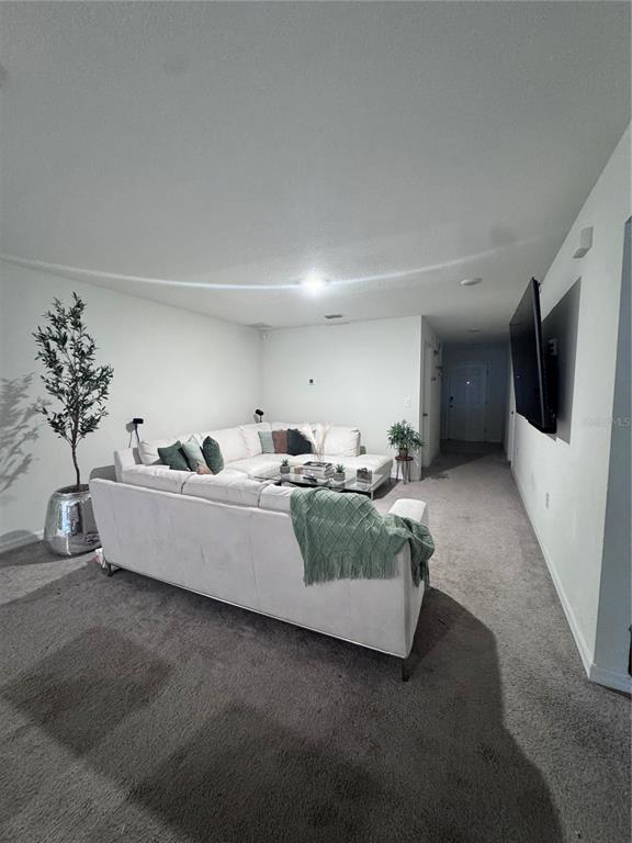 A living room features a large white sectional sofa, gray carpeting, and a wall-mounted television — 360 TOWNS CIRCLE, HAINES CITY, FL