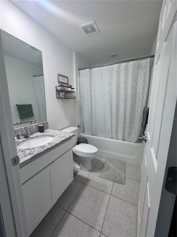 A bathroom featuring a granite vanity, white cabinets, and a shower-tub combination with a curtain — 360 TOWNS CIRCLE, HAINES CITY, FL