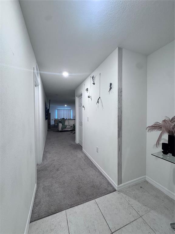 A hallway with carpeted flooring leads from a tiled entryway toward a living area — 360 TOWNS CIRCLE, HAINES CITY, FL