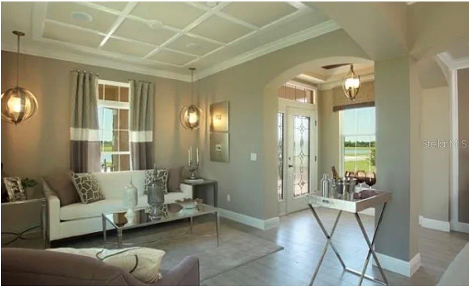 A living room features a coffered ceiling, neutral walls, and a glass-topped coffee table — 11835 GOLD CREEK TRAIL, WINDERMERE, FL