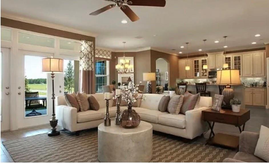 A living room with a white sectional sofa, a round coffee table, and an open kitchen — 11835 GOLD CREEK TRAIL, WINDERMERE, FL