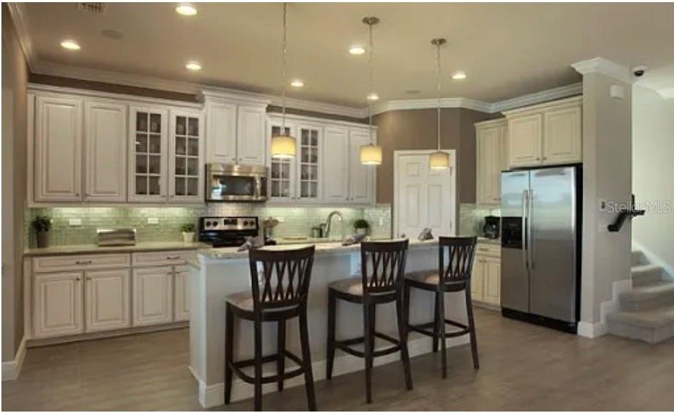 A kitchen with white cabinets, stainless steel appliances, a breakfast bar, and pendant lighting — 11835 GOLD CREEK TRAIL, WINDERMERE, FL
