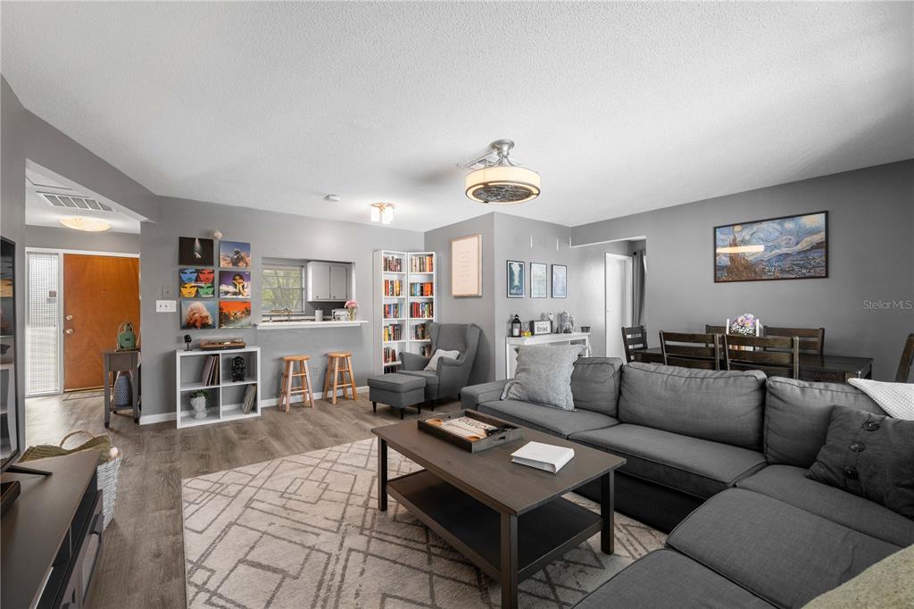 A living room with gray walls, wood-look flooring, a sectional sofa, and an open kitchen pass-through — 1960 UNION STREET UNIT 28, CLEARWATER, FL