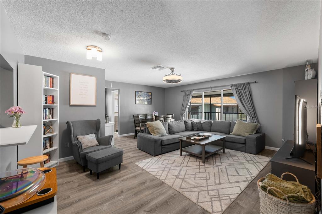 A living room with gray walls, wood-look flooring, a sectional sofa, and a dining area — 1960 UNION STREET UNIT 28, CLEARWATER, FL