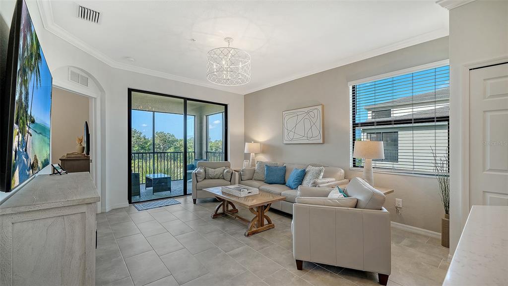 A living room features light tile floors, a neutral sofa, two armchairs, and a sliding door — 18114 GAWTHROP DRIVE UNIT 308, LAKEWOOD RANCH, FL