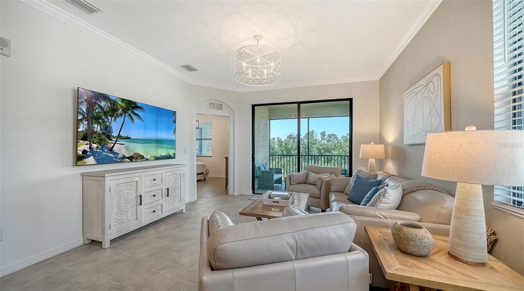 A living room features light tile floors, a large television, and a sliding glass door — 18114 GAWTHROP DRIVE UNIT 308, LAKEWOOD RANCH, FL