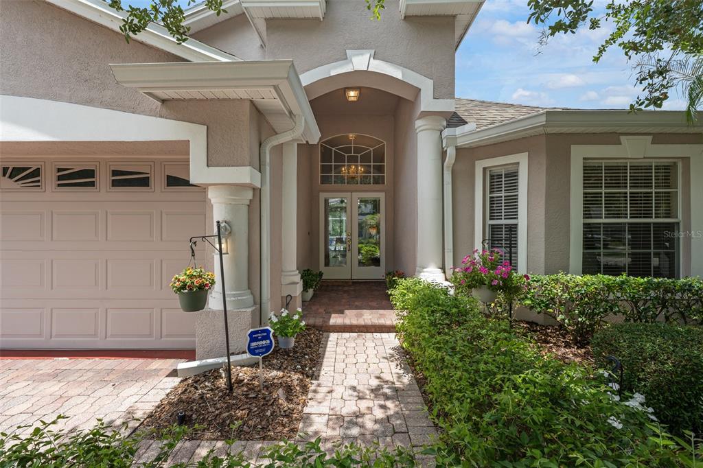 The exterior of a house features a brick walkway leading to a double-door entryway — 16230 NOTTINGHAM PARKWAY, TAMPA, FL