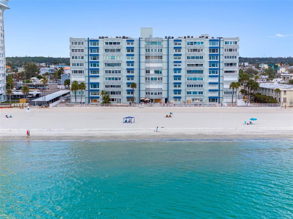 An aerial view of a multi-story apartment building situated directly on a sandy beach — 17400 GULF BOULEVARD UNIT I3, REDINGTON SHORES, FL