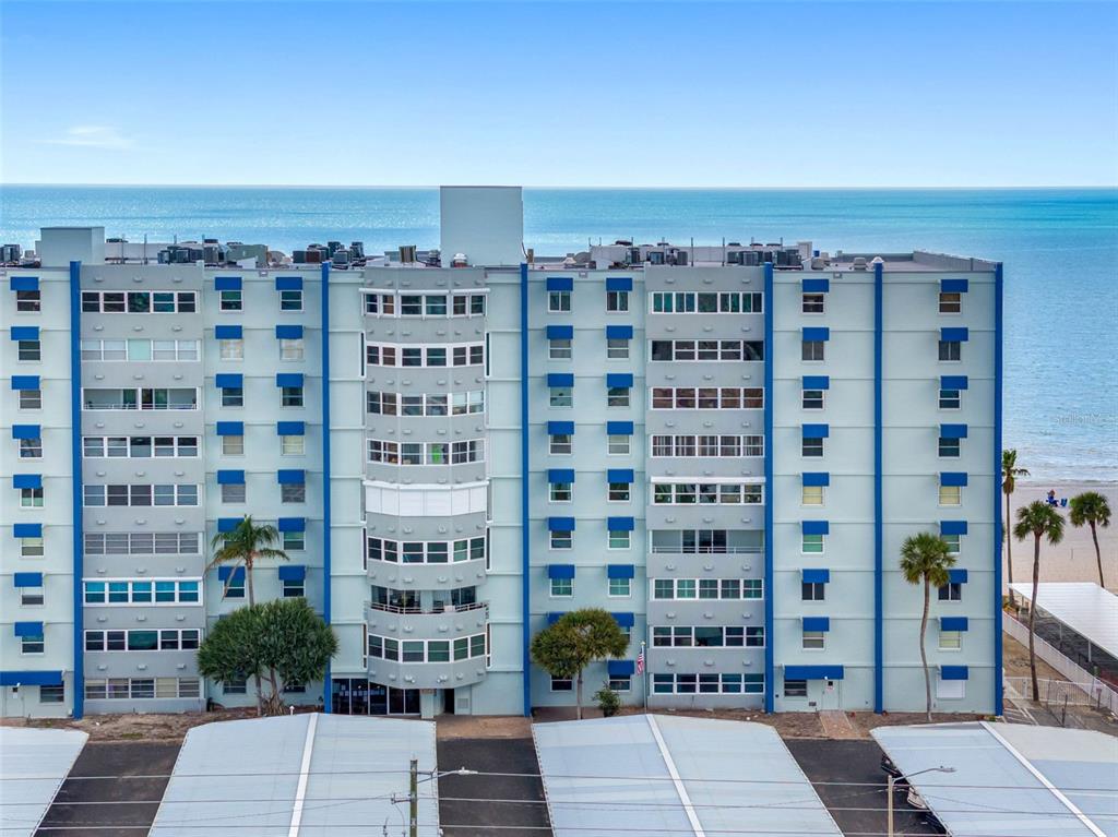 An exterior view of a multi-story apartment building with blue accents located near the ocean — 17400 GULF BOULEVARD UNIT I3, REDINGTON SHORES, FL