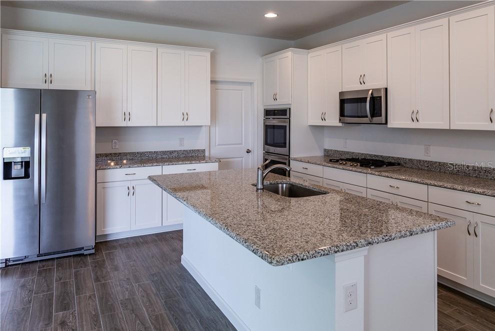 A kitchen with white cabinets, granite countertops, stainless steel appliances, and a central island — 7591 TANGERINE KNOLL LOOP, WINTER GARDEN, FL