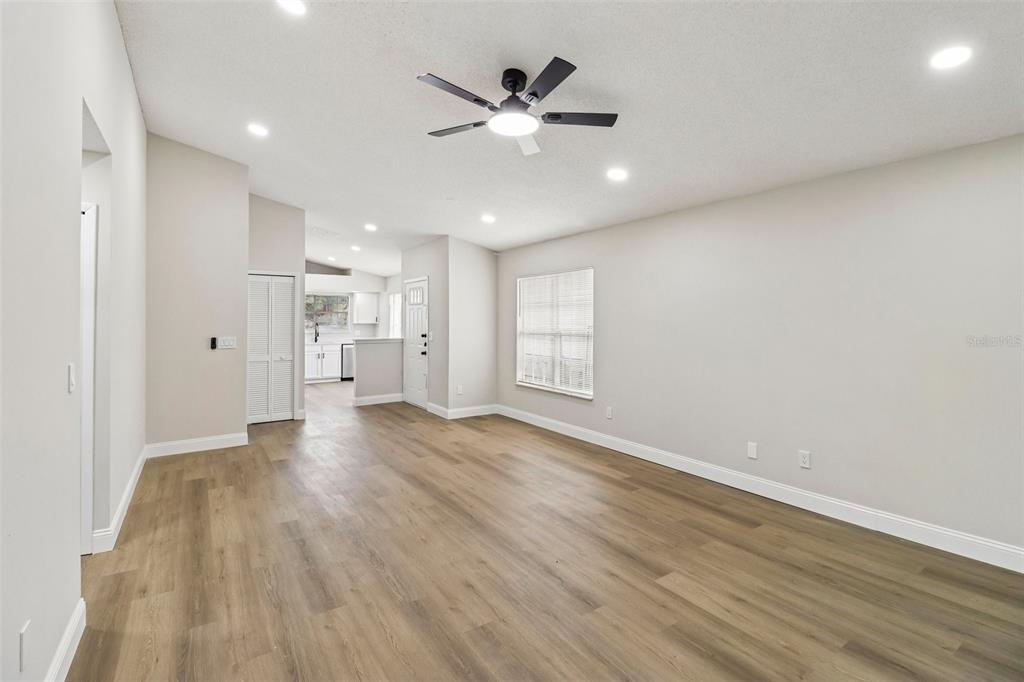 An empty living room features light-colored walls, wood-look flooring, a ceiling fan, and recessed lighting — 106 LAMPLIGHTER DRIVE, SANFORD, FL