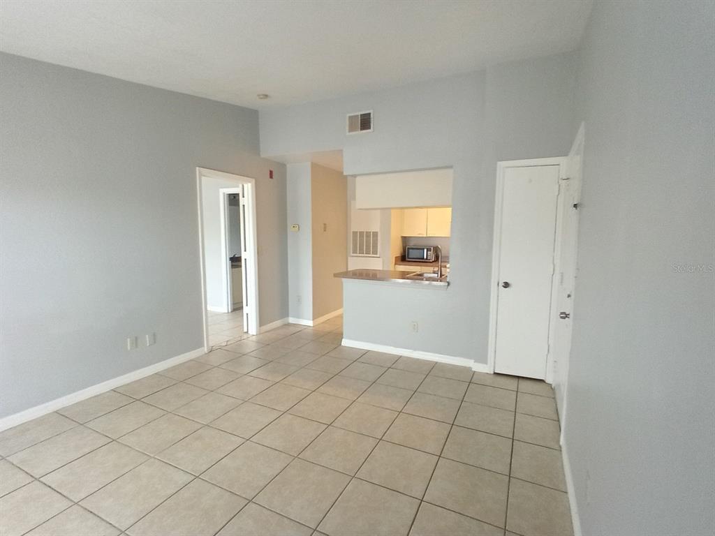 An interior view of a living room with tile flooring and an open kitchen pass-through — 2550 N ALAFAYA TRAIL UNIT 4305, ORLANDO, FL