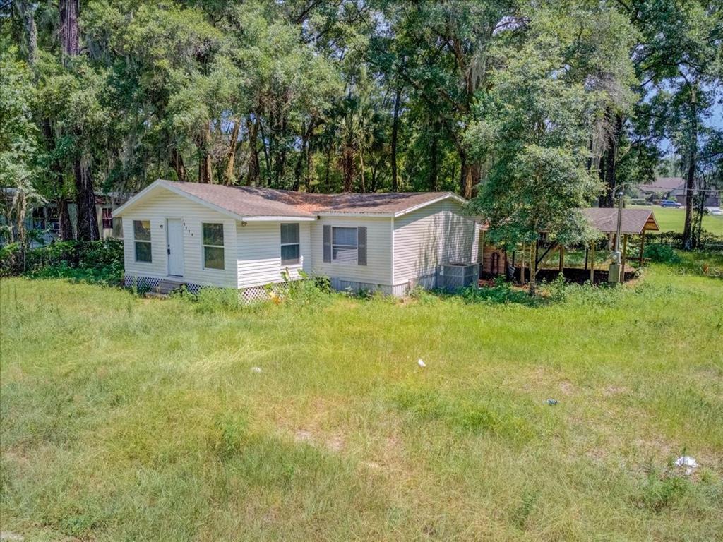 A light-colored single-story house sits on a grassy lot surrounded by trees — 5530 SE 41ST ST OCALA ,FL, OCALA, FL