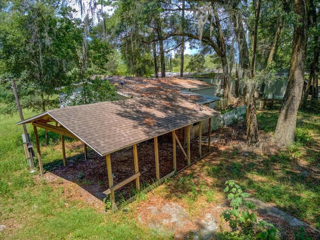 An elevated view of a house with a large wooden carport and a shingled roof — 5530 SE 41ST ST OCALA ,FL, OCALA, FL