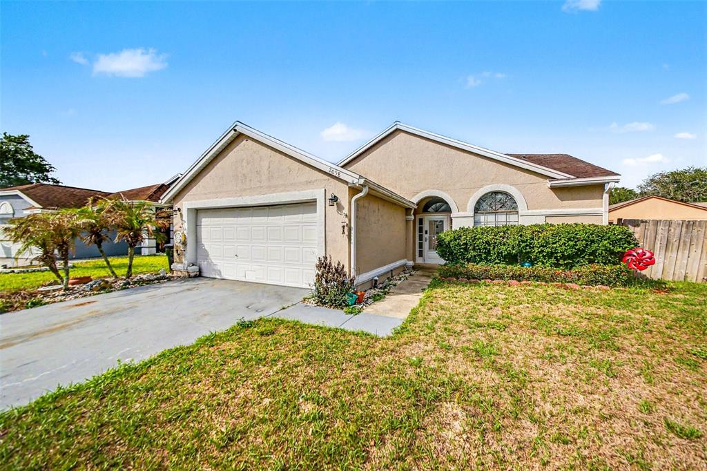 A single-story house with a beige stucco exterior, a two-car garage, and a front lawn — 2058 SUE ELLEN COURT, APOPKA, FL
