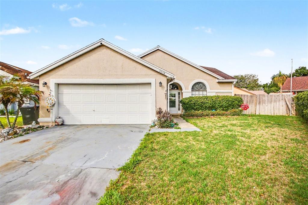 A single-story house with a beige stucco exterior, a two-car garage, and a front lawn — 2058 SUE ELLEN COURT, APOPKA, FL