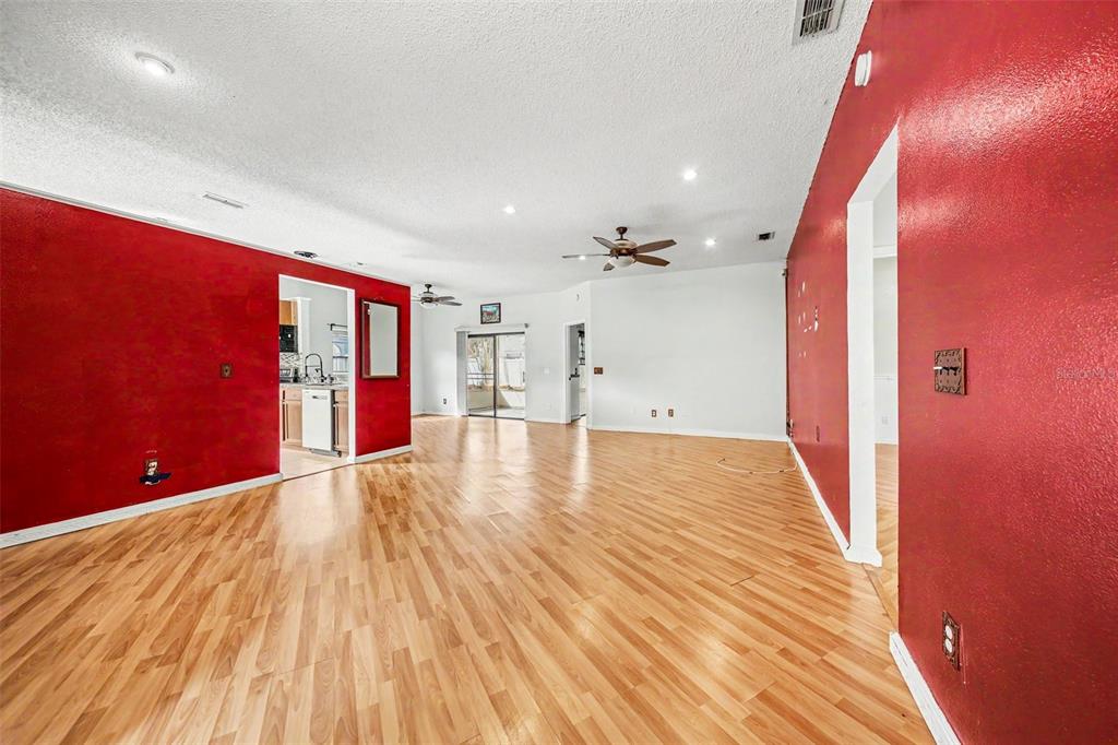 A living room features red accent walls, light wood flooring, and a ceiling fan — 2058 SUE ELLEN COURT, APOPKA, FL