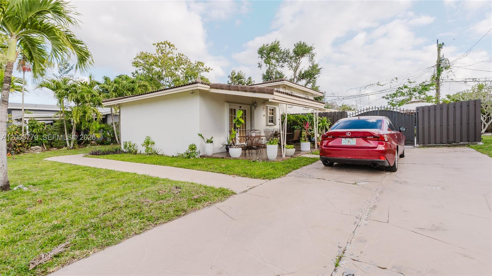 A single-story house with a white exterior, a covered porch, and a red car parked outside — 1300 NE 204th St, Miami FL 33179, MIAMI, FL