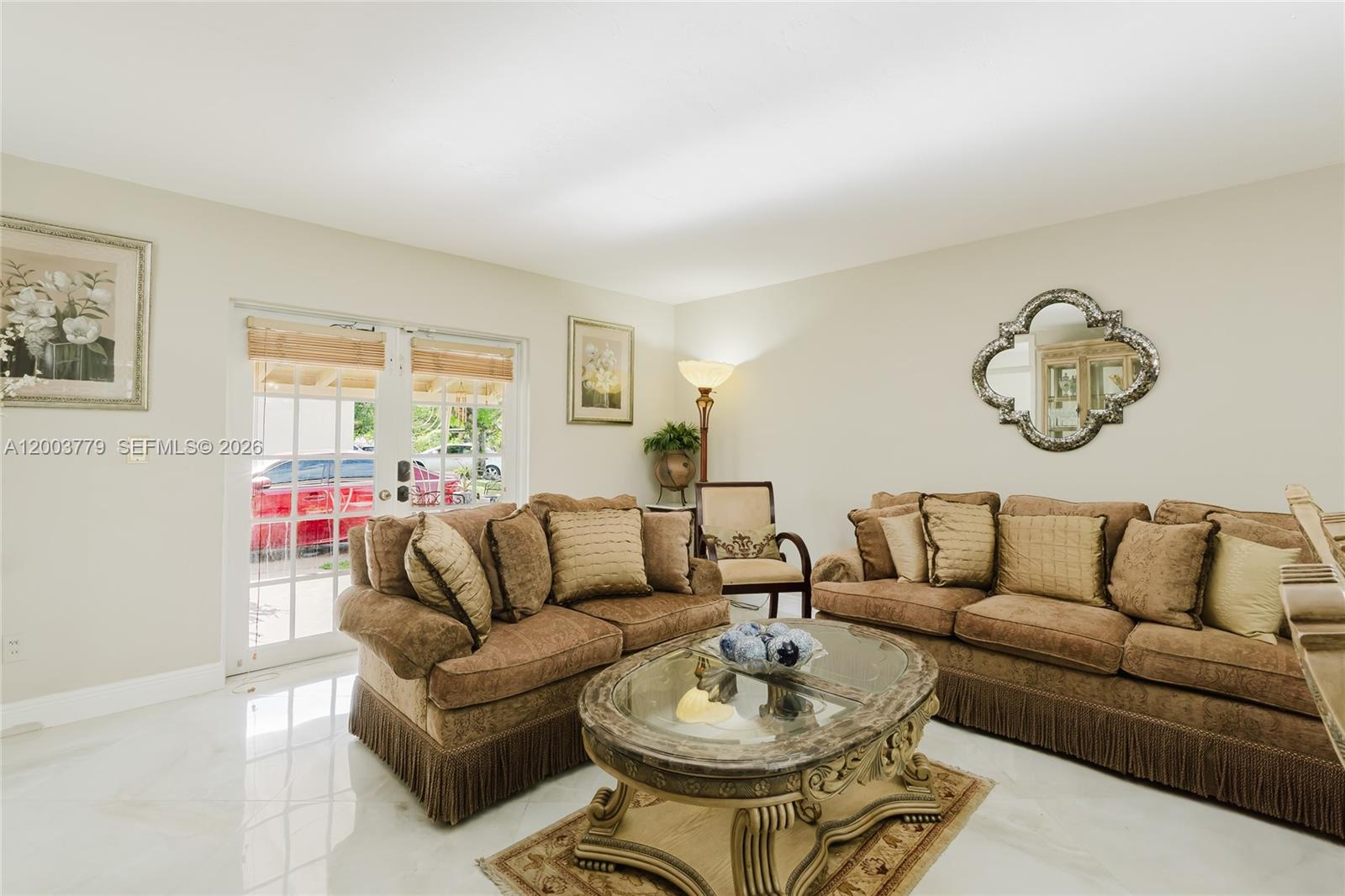 A living room features two brown sofas, a glass-topped coffee table, and glass doors — 1300 NE 204th St, Miami FL 33179, MIAMI, FL
