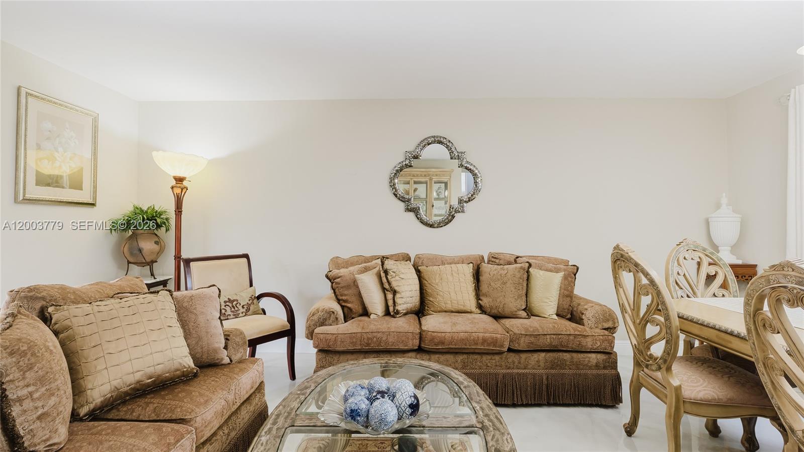 A living room features a brown sofa, matching armchair, glass coffee table, and dining chairs — 1300 NE 204th St, Miami FL 33179, MIAMI, FL