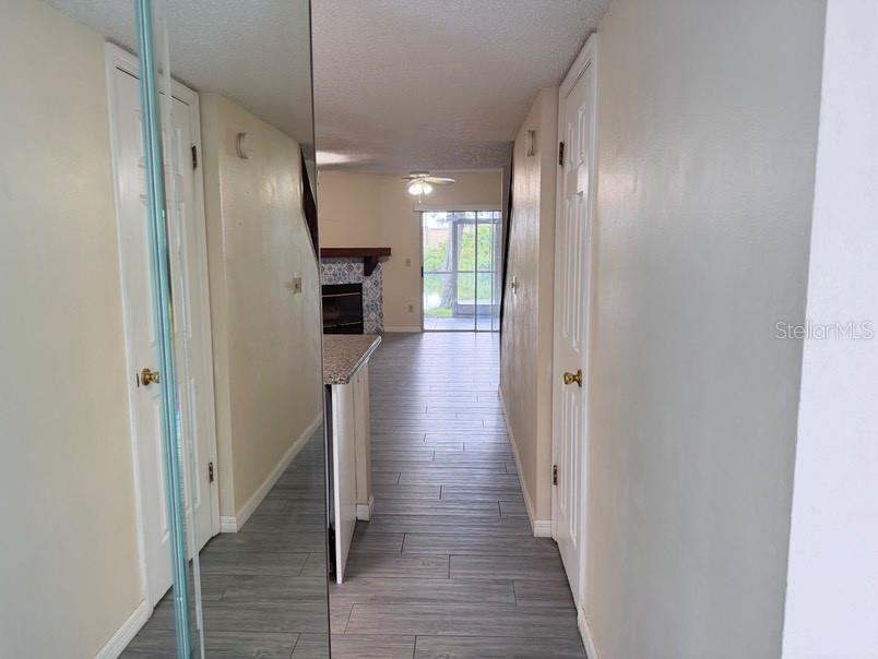 A hallway with light wood-look tile flooring leads toward a living area with a fireplace — 7514 COLONIAL COURT, TAMPA, FL