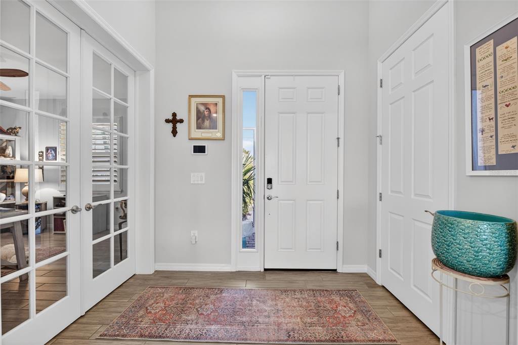 A bright entryway features a white front door, glass-paneled double doors, and a patterned area rug — 8117 THRUSO ROAD, PORT CHARLOTTE, FL