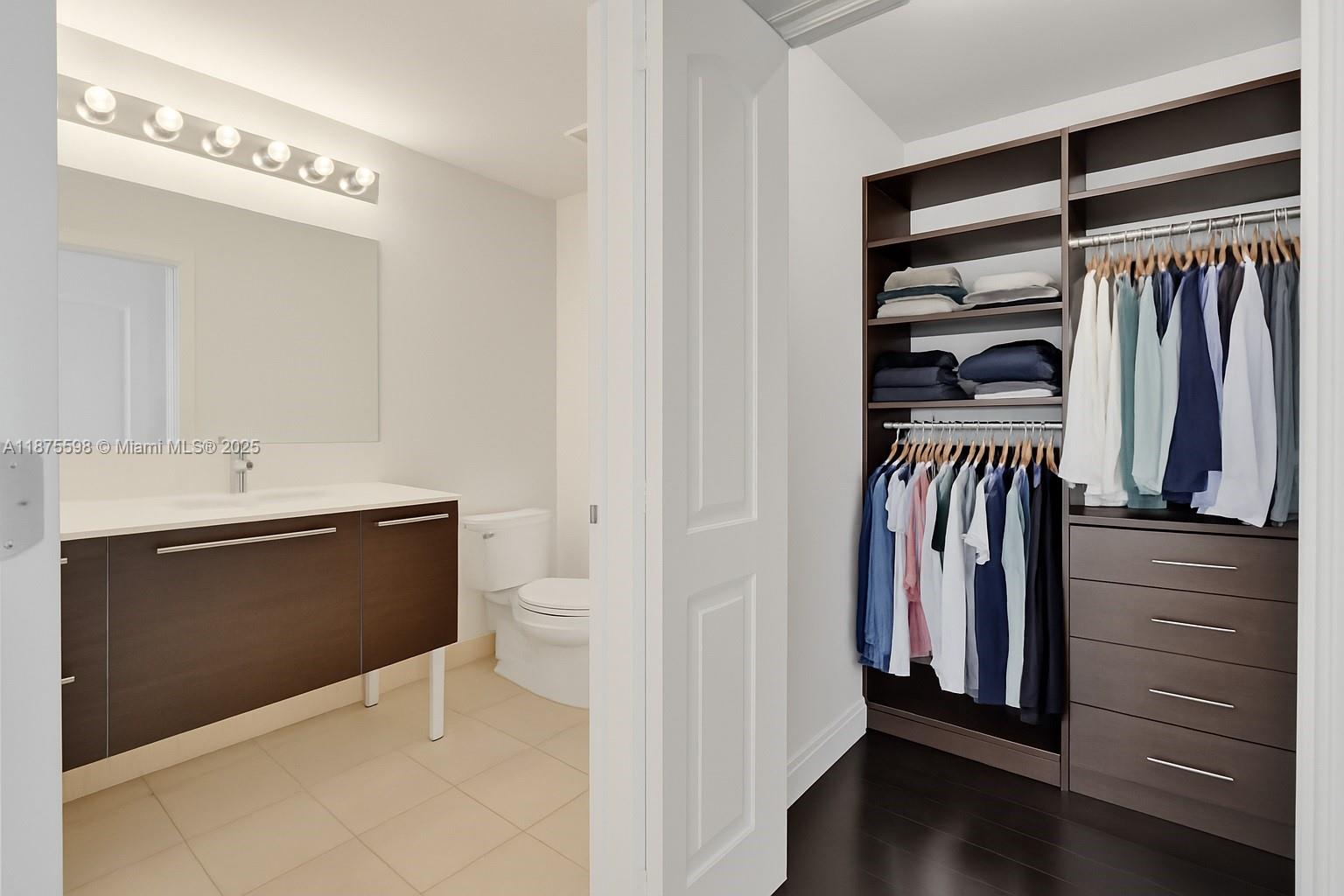 A bathroom with a vanity and toilet sits adjacent to a walk-in closet with shelving — 1900 N Bayshore Dr # 3207, Miami FL 33132, MIAMI, FL
