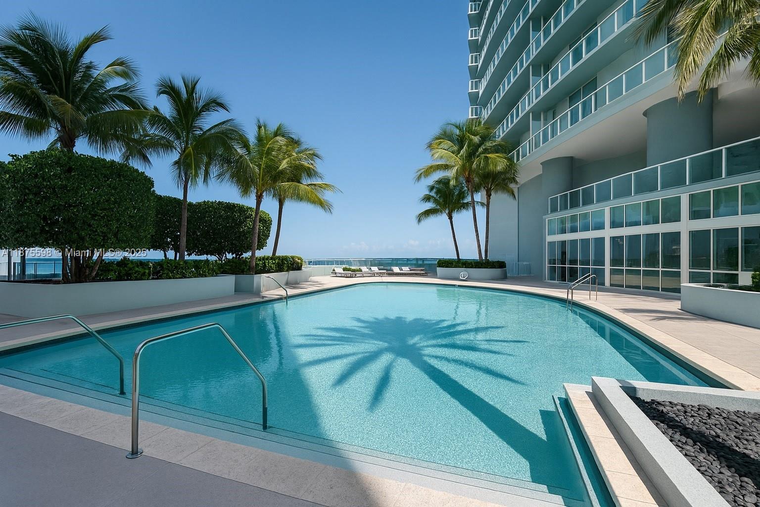 An outdoor swimming pool is surrounded by palm trees and a modern high-rise building — 1900 N Bayshore Dr # 3207, Miami FL 33132, MIAMI, FL