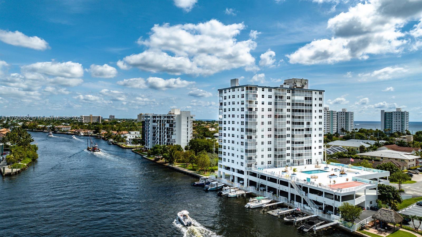 An aerial view shows a waterfront high-rise apartment building with a pool and boat docks — 1505 N Riverside Dr # 604, Pompano Beach FL 33062, POMPANO BEACH, FL