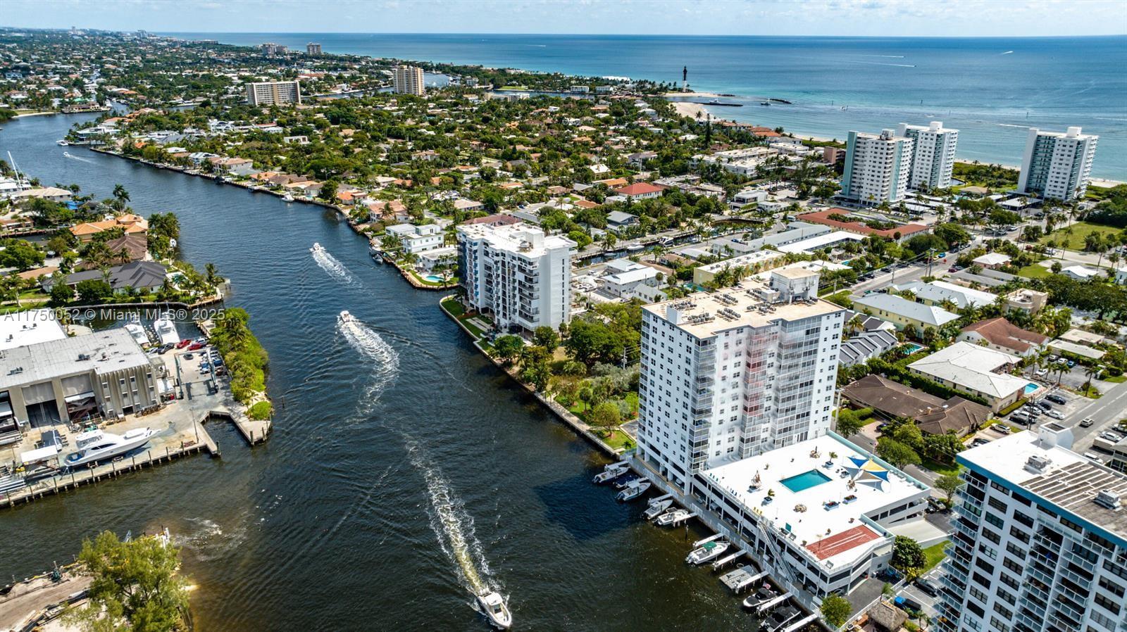 An aerial view shows high-rise residential buildings along a canal leading to the ocean — 1505 N Riverside Dr # 604, Pompano Beach FL 33062, POMPANO BEACH, FL