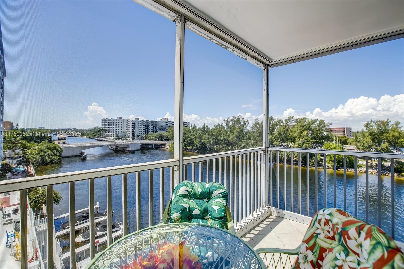 A screened-in balcony overlooks a river with a bridge, boats, and lush trees — 1505 N Riverside Dr # 604, Pompano Beach FL 33062, POMPANO BEACH, FL