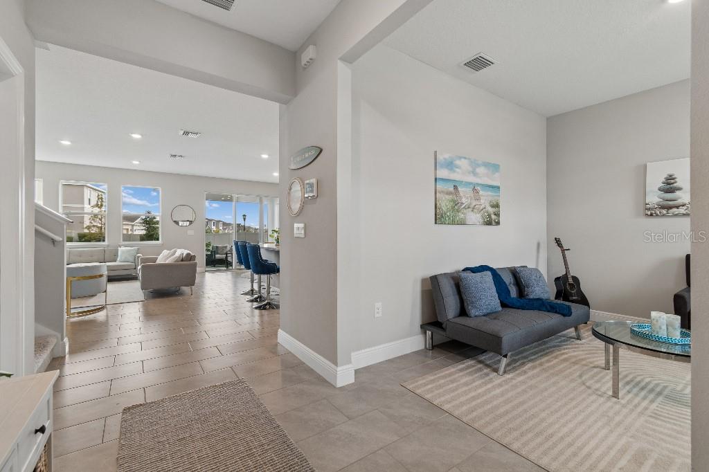 A bright living area with tile flooring leads to an open-concept kitchen and family room — 116 BRIGHT IBIS AVENUE, APOLLO BEACH, FL