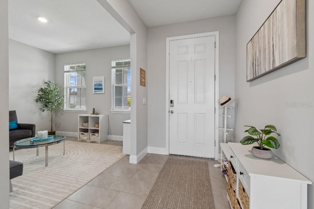An entryway with tile flooring leads into a living area with a rug and windows — 116 BRIGHT IBIS AVENUE, APOLLO BEACH, FL