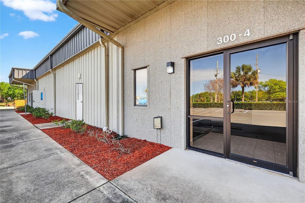 The exterior of a commercial building features a glass entrance door labeled 300-4 — 300 RICHEY ROAD UNIT 3 & 4, LEESBURG, FL