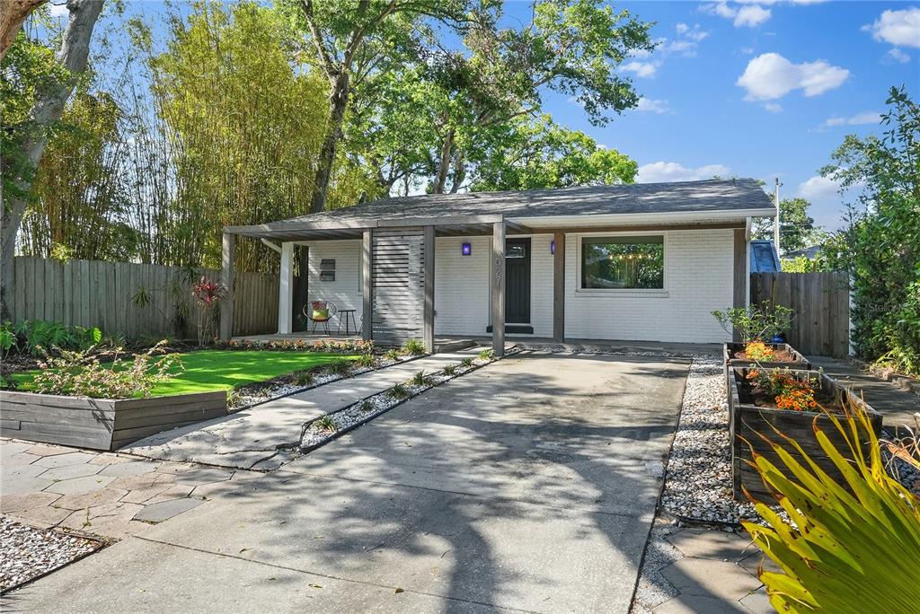 A white brick house features a wooden pergola, a concrete driveway, and raised garden beds — 3027 BURLINGTON AVENUE N, ST PETERSBURG, FL