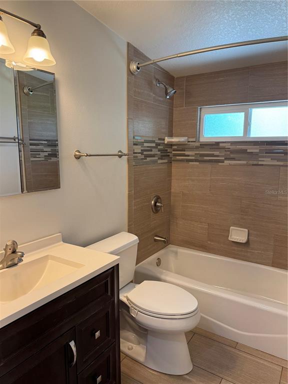 A bathroom features a dark wood vanity, a white toilet, and a tiled shower-tub combination — 1026 36TH AVENUE E, ELLENTON, FL